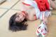 A woman in a red and white outfit laying on a tatami mat.