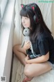 A woman sitting on a bed with a stuffed animal and headphones.