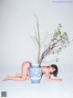 A woman laying on the ground next to a blue and white vase.