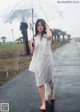 A woman walking down a wet road holding an umbrella.