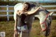 A woman standing next to a white horse in a field.