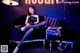 A woman sitting on a couch in front of a neon sign.