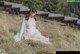 A naked woman sitting in a field of tall grass.