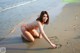 A woman in a bikini writing in the sand on the beach.