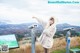 A woman in a white coat pointing at a sign.