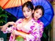 Two young women in kimonos holding umbrellas in the rain.